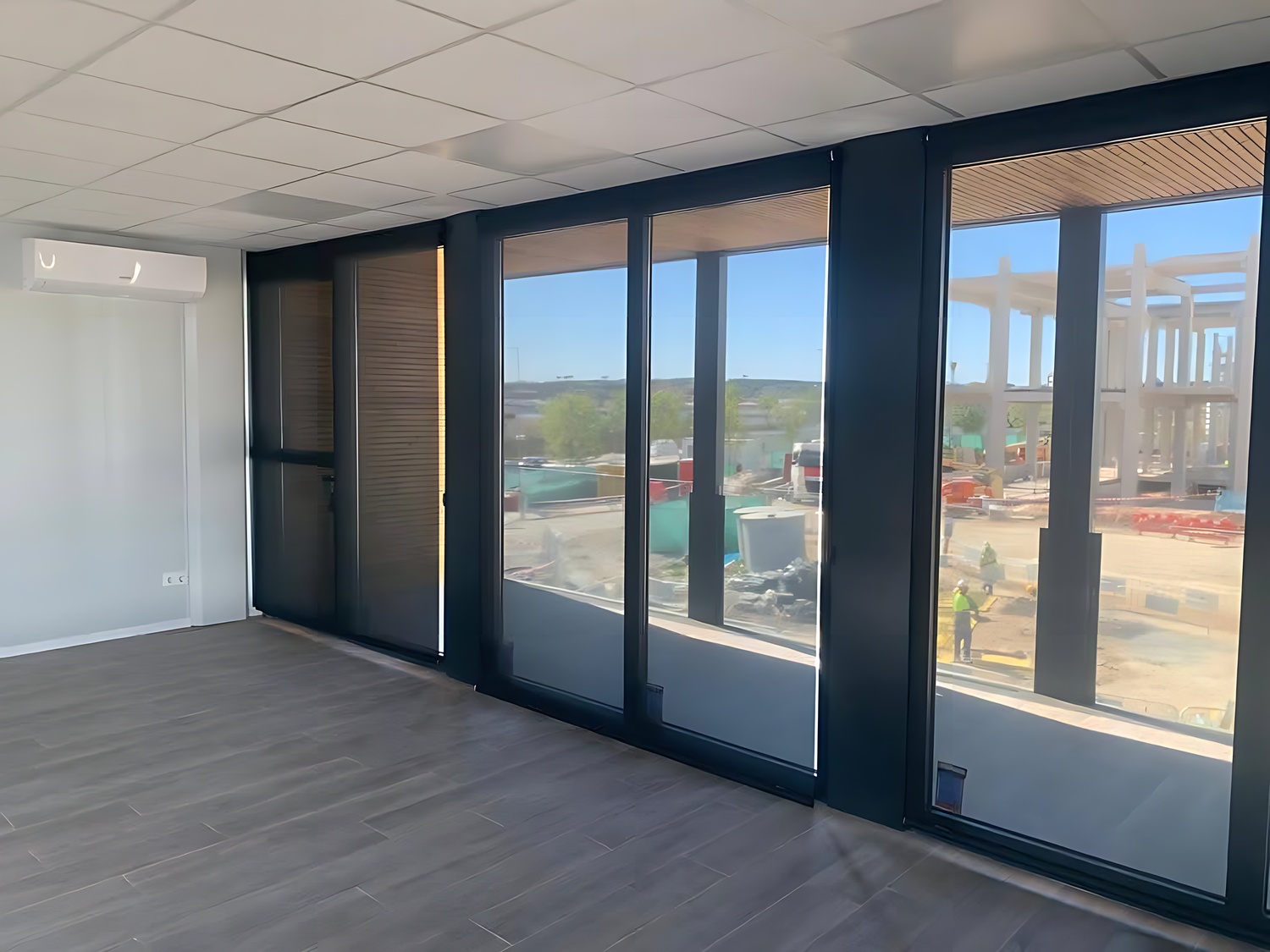 Vista interior de oficina modular prefabricada exterior con grandes ventanales y doble altura